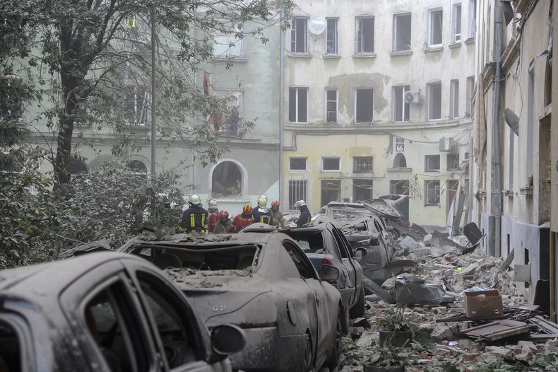 Efectivos de los servicios de emergencia se reúnen en el exterior de edificios dañados mientras buscan a posibles víctimas tras un ataque ruso sobre Leópolis, Ucrania, el 6 de julio de 2023. (AP Foto/Mykola Tys)