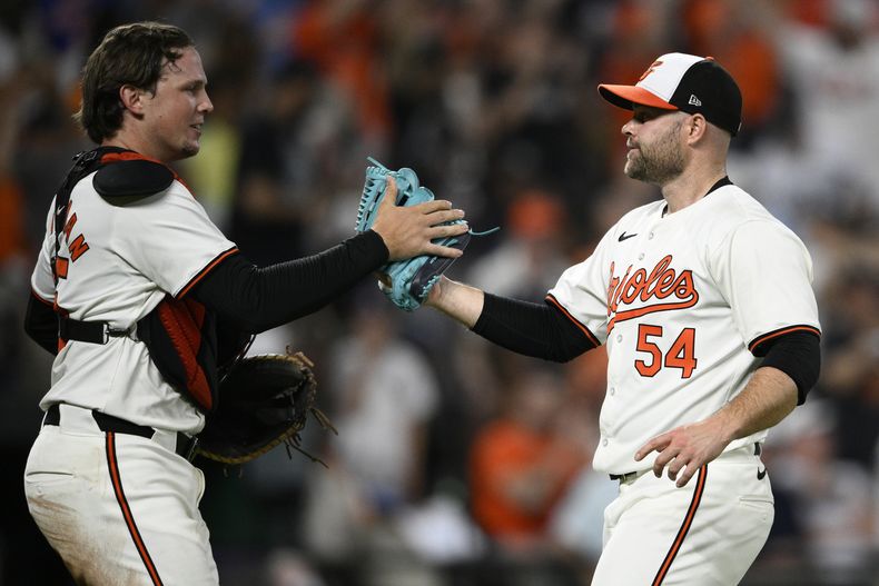 El relevista de los Orioles de Baltimore, Danny Coulombe (54), y el receptor Adley Rutschman, a la izquierda, celebran después de un partido de béisbol contra los Yankees de Nueva York, el lunes 29 de abril de 2024, en Baltimore. Los Orioles ganaron 2-0. (AP Foto/Nick Wass)