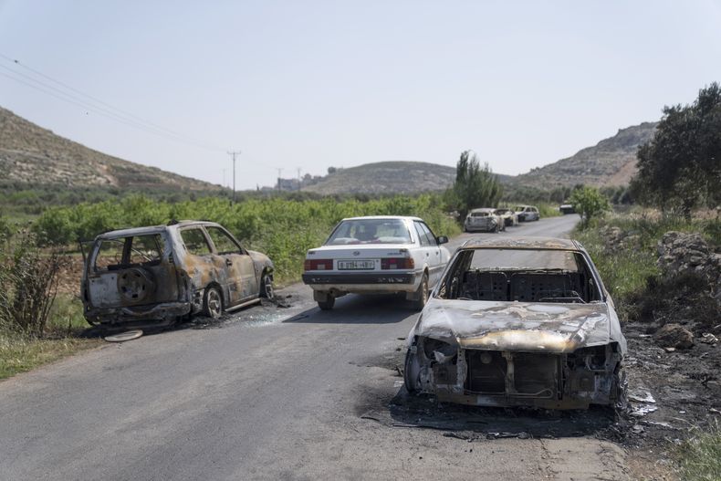 Vehículos calcinados, vistos a ambos lados de una carretera en la localidad cisjordana de al-Mughayyir, el 13 de abril de 2024. (AP Foto/Nasser Nasser)