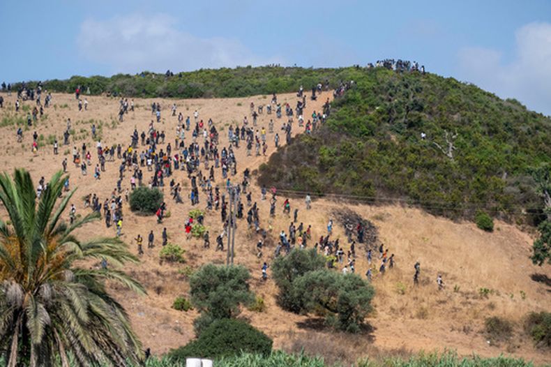 Varios migrantes se reúnen en una colina mientras intentan cruzar desde la ciudad fronteriza de Fnideq hacia el enclave español de Ceuta, el sábado 15 de agosto de 2026. (AP Foto)