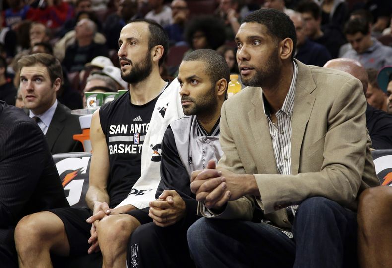 Tim Duncan, desde la derecha, Tony Parker y Manu Gin&oacute;bili observan desde la banca de los Spurs de San Antonio el partido ante los 76ers de Filadelfia, el lunes 1 de diciembre de 2014. (AP Foto/Matt Slocum)