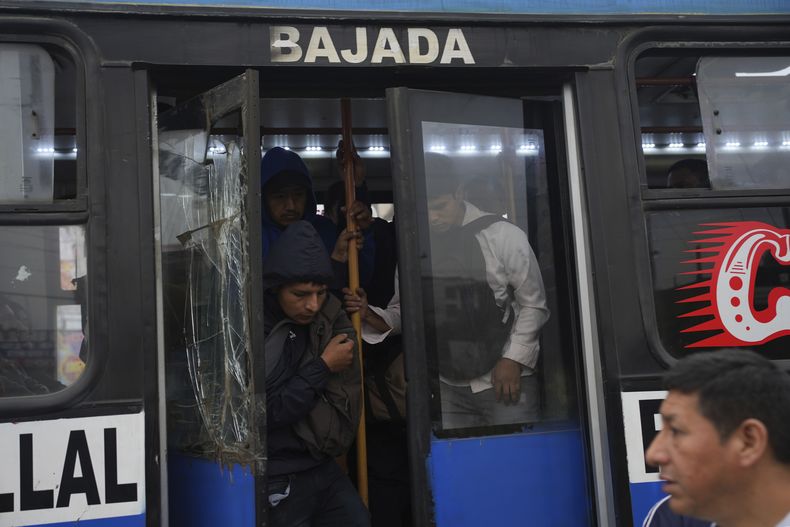 Los viajeros se bajan de uno de los pocos autobuses en funcionamiento durante una huelga del transporte público para exigir que el gobierno proporcione seguridad contra la extorsión en Lima, Perú, el miércoles 23 de octubre de 2024. (AP Foto/Guadalupe Pardo)