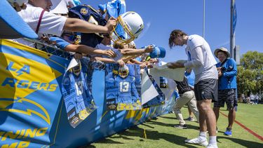 Justin Herbert, derecha, quarterback de los Chargers de Los Ángeles, firma autógrafos para los fanáticos después del primer entrenamiento del campamento de prácticas del equipo en Costa Mesa, California, el miércoles 26 de julio de 2023. (Mark Rightmire/The Orange County Register vía AP)