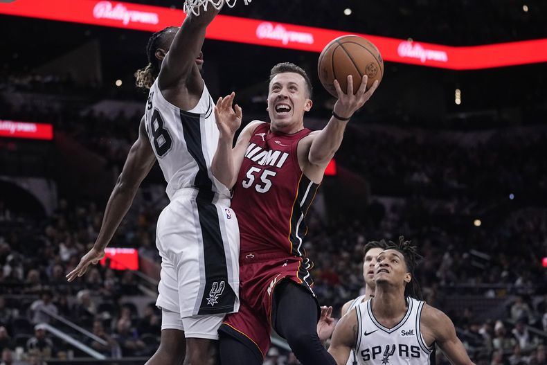 Duncan Robinson (55), del Heat de Miami, busca encestar una canasta con la marca defensiva de Charles Bassey (28), de los Spurs de San Antonio, durante la primera mitad del juego de baloncesto de la NBA, en San Antonio, el domingo 12 de noviembre de 2023. (AP Foto/Eric Gay)