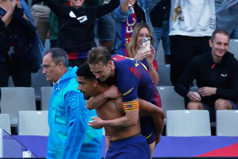 Frenkie de Jong del Barcelona abraza a su compañero Ronald Araujo tras anotar en el encuentro ante el Girona en La Liga el sábado 18 de octubre del 2025. (AP Photo/Joan Monfort)