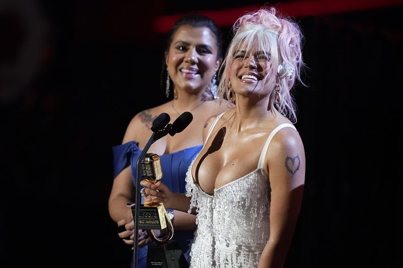 Karol G, derecha, recibe el Premio Espíritu de la Esperanza en los Premios Billboard de la Música Latina el jueves 5 de octubre de 2023, en Coral Gables, Florida. (Foto AP/Marta Lavandier)