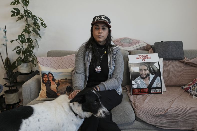 Ilana Gritzewsky, una de las rehenes que estuvo 55 días en manos de Hamás, posa para un retrato en su apartamento en Kiryat Gat, Israel, el 15 de diciembre de 2024, cerca de fotos de su novio, Matan Zangauker, quien sigue retenido como rehén en Gaza. (AP Foto/Tsafrir Abayov)