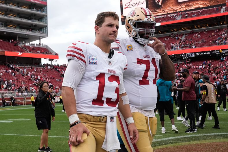 El quarterback de los 49ers de San Francisco, Brock Purdy (13), y el tackle ofensivo, Trent Williams (71), abandonan el campo después de un juego de fútbol americano de la NFL contra los Jaguars de Jacksonville en Santa Clara, California, el domingo 28 de septiembre de 2025. (AP Photo/Godofredo A. Vásquez)