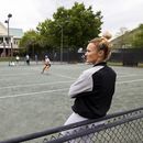 Iris Harris se recarga en una cerca mientras observa una práctica en el torneo de Charleston, el 3 de abril de 2023. Harris es integrante del Programa de Inclusión de Entrenadoras (AP Foto/Mic Smith)