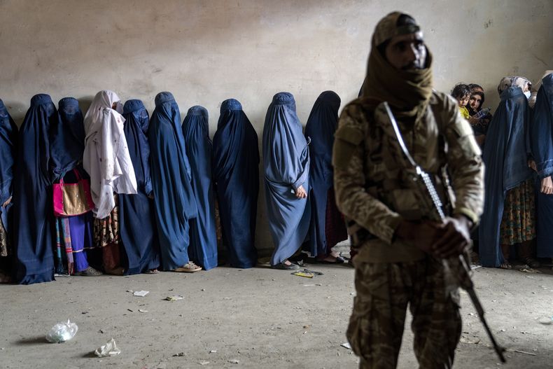 Un combatiente talibán frente a un grupo de mujeres que esperan recibir comida repartida por un grupo humanitario en Kabul, Afganistán, el 23 de mayo del 2023. (AP foto/Ebrahim Noroozi)