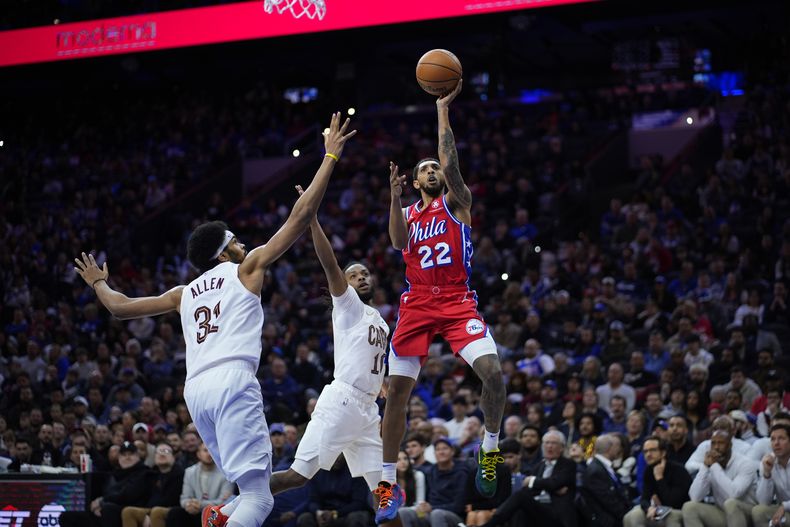 Cameron Payne, de los 76ers de Filadelfia, salta para disparar ante Darius Garland (centro) y Jarrett Allen, de los Cavaliers de Cleveland, en el partido del viernes 23 de febrero de 2024 (AP Foto/Matt Slocum)