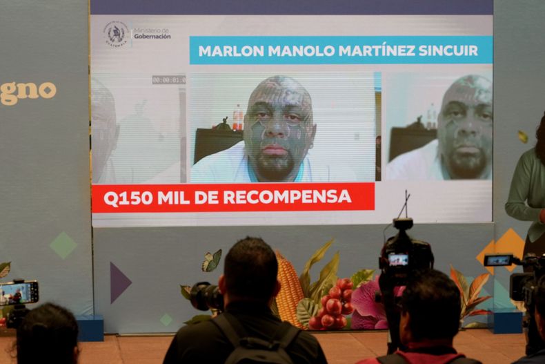 La fotografía del fugitivo Marlon Manolo Martínez Sincuir, de la pandilla Barrio 18, se muestra en una pantalla que ofrece una recompensa por información para recapturarlo a él y a otros presos que escaparon de una prisión de máxima seguridad, durante una conferencia de prensa del ministro del Interior, Francisco Jiménez, en el Palacio Nacional en la Ciudad de Guatemala, el lunes 13 de octubre de 2025. (AP Foto/Moisés Castillo)