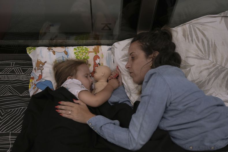 Tehila Alush y su hija Ariel Asraf, de 3 años, descansan tras refugiarse en una estación de metro como medida de precaución ante posibles ataques con misiles iraníes, en Ramat Gan, cerca de Tel Aviv, Israel, el martes 17 de junio de 2025. (AP Foto/Oded Balilty)