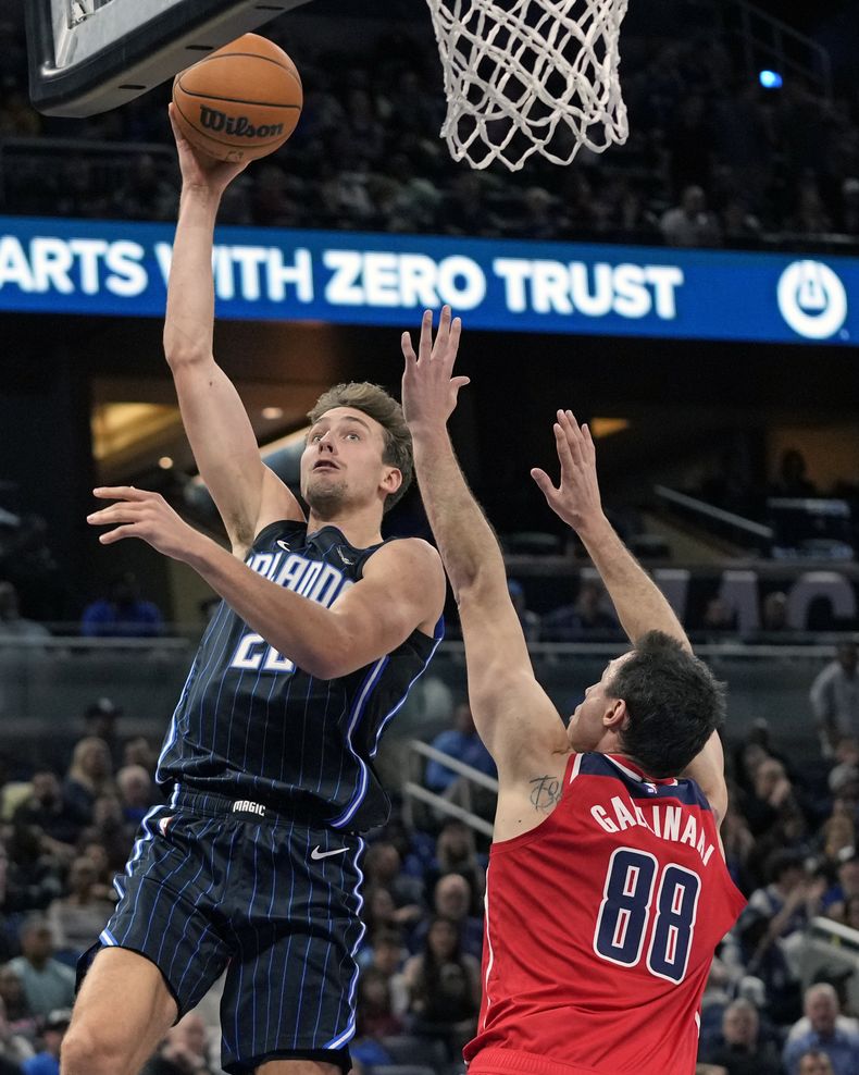 El alero del Magic de Orlando Franz Wagner lanza el balón sobre el alero Danilo Gallinari de los Wizards de Washington en el encuentro del viernes 1 de diciembre del 2023. (AP Foto/John Raoux)