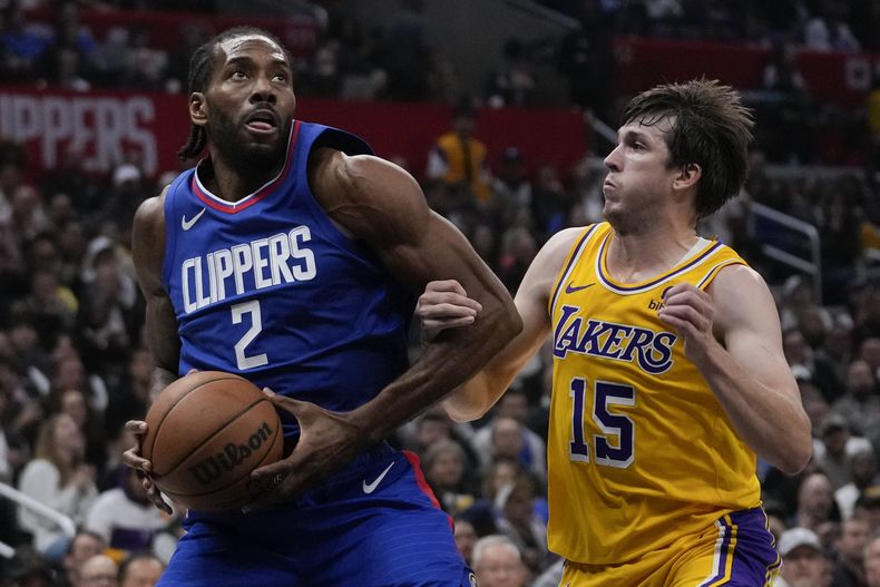 Kawhi Leonard, de los Clippers de Los Ángeles, controla el balón frente a Austin Reaves, de los Lakers de la misma ciudad, en el encuentro del martes 23 de enero de 2024 (AP Foto/Ashley Landis)