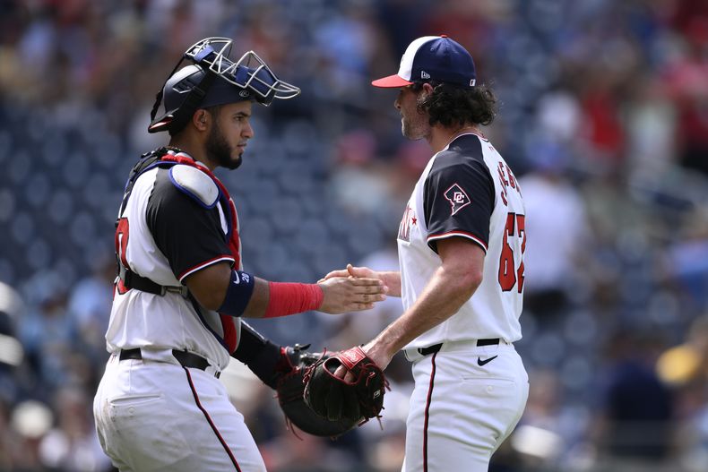 El relevista de los Nacionales de Washington, Kyle Finnegan (derecha) y el receptor venezolano Keibert Ruiz (izquierda) celebran luego del juego de béisbol ante los Cervecceros de Milwaukee, el domingo 4 de agosto de 2024, en Washington. (AP Foto/Nick Wass)