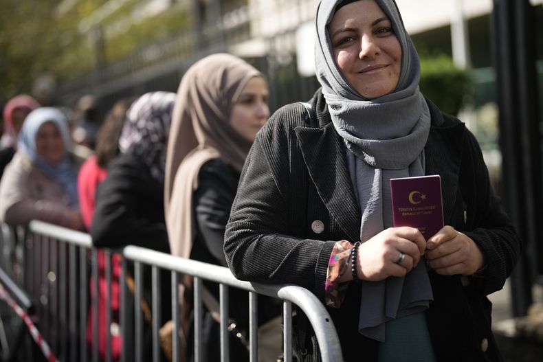 Una ciudadana turca sostiene su pasaporte mientras espera en fila para votar, en el exterior del consulado de Turquía en Boulogne-Billancourt, a las afueras de París, el 27 de abril de 2023. (AP Foto/Christophe Ena)