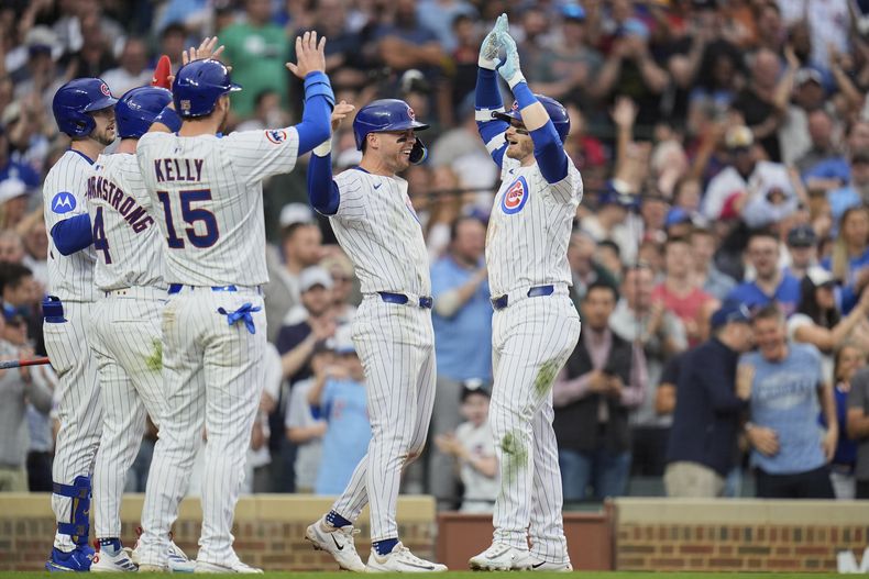 Ian Happ, de los Cachorros de Chicago, a la derecha, choca los cinco con Nico Hoerner después de conectar un grand slam durante la séptima entrada de un juego de béisbol contra los Diamondbacks de Arizona, el viernes 18 de abril de 2025, en Chicago. (AP Foto/Erin Hooley)