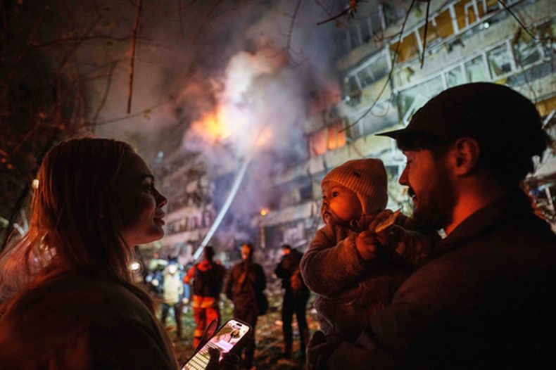 Victoria Deineko, su esposo, Ievhen Deineko y su hija, Mia, se ven junto a un edificio residencial de varias plantas dañado en Kiev, Ucrania, el martes 13 de octubre de 2026. (AP Foto/Evgeniy Maloletka)