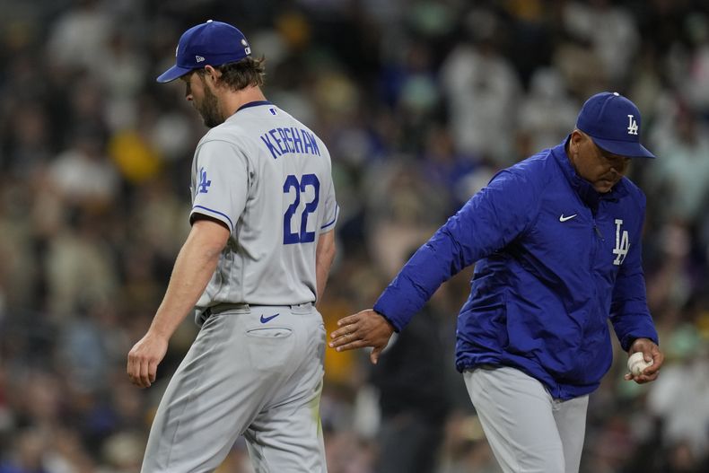 Dave Roberts, derecha, manager de los Dodgers de Los Ángeles, recibe la pelota de manos del lanzador Clayton Kershaw, izquierda, mientras éste sale del partido durante la quinta entrada, el viernes 5 de mayo de 2023, en San Diego. (AP Foto/Gregory Bull)