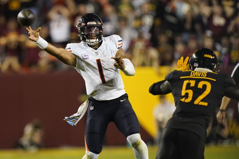 Justin Fields (1), quarterback de los Bears de Chicago, lanza el balón ante la presión del linebacker de los Commanders de Washington Jamin Davis (52), durante la segunda mitad del juego de la NFL, el jueves 5 de octubre de 2023, en Landover, Maryland. (AP Foto/Stephanie Scarbrough)