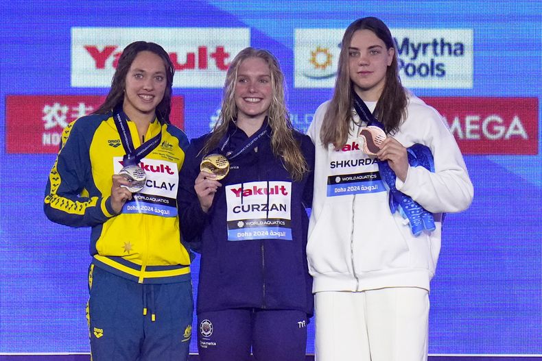 La australiana Jaclyn Barclay, con la medalla de plata; la estadounidense Claire Curzan, con la medalla de oro; y Anastasiya Shkurdai, que ganó bronce, posan en el podio en el campeonato mundial de natación en Doha Qatar el sábado 17 de febrero del 2024. (AP Foto/Hassan Ammar)