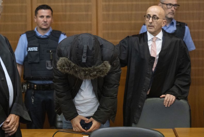 Un médico sirio, en el centro, acusado de tortura y crímenes de guerra en su Siria natal, se ve junto a su abogado, Oussama Al-Agi, a la derecha, en el Alto Tribunal Regional antes de que se anunciara el veredicto en Fráncfort, Alemania, el lunes 16 de junio de 2025. (Boris Roessler/dpa via AP)