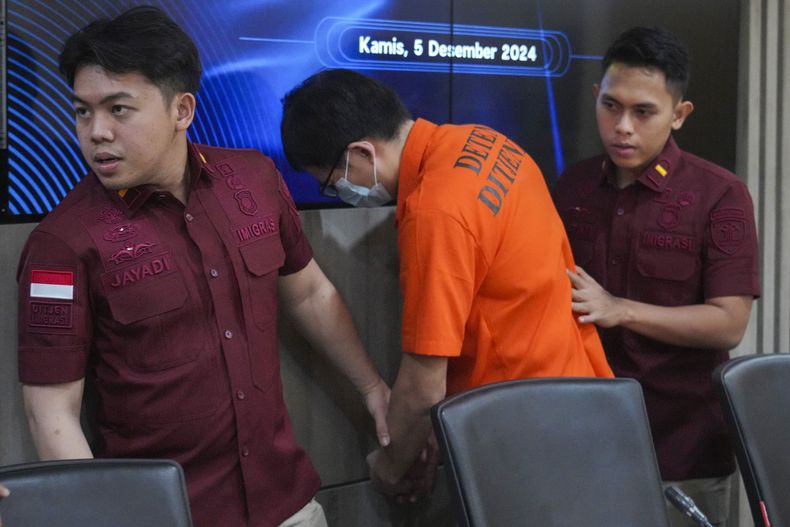 Oficiales de migración de Indonesia escoltan a Yan Zhenxing, un ciudadano chino arrestado por lavado de dinero, durante una conferencia de prensa en Yakarta, el 5 de diciembre de 2024. (AP Foto/Achmad Ibrahim)