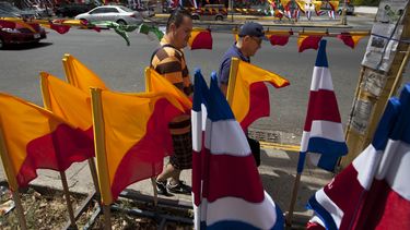 americateve | Dos hombres caminan frente a banderas de Costa Rica y de partidos pol&iacute;ticos en San Jos&eacute;, el s&aacute;bado 5 de abril de 2014. Costa Rica vota el domingo en segunda vuelta de las elecciones presidenciales, para elegir entre el opositor Luis G
