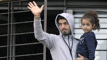 americateve | El uruguayo Luis Su&aacute;rez carga a su hija y saluda a los seguidores que acudieron a manifestarle apoyo, desde el balc&oacute;n de su casa en las afueras de Montevideo, el viernes 27 de junio de 2014 (AP Foto/Matilde Campodonico)