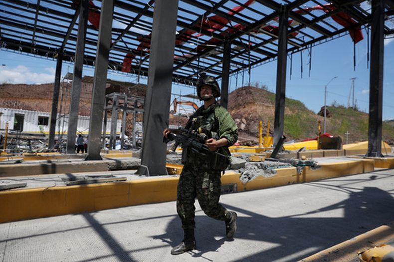 Un soldado camina por una estación de peaje de la Carretera Panamericana, dañada por la explosión de un coche bomba que el ejército atribuyó a grupos disidentes de las FARC, el sábado 8 de agosto de 2026, en Santander de Quilichao, Colombia. (AP Foto/Santiago Saldarriaga)