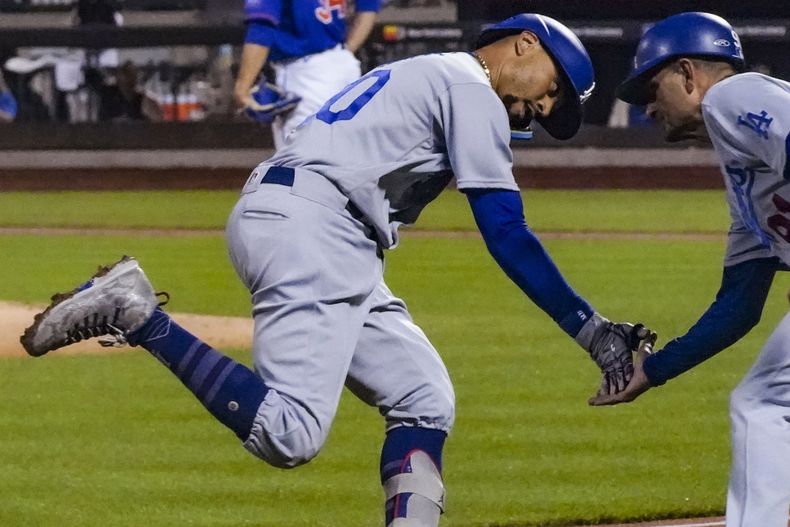 Mookie Betts, de los Dodgers de Los Ángeles, festeja con el coach de tercera Dino Ebel, luego de conectar un jonrón en el juego del sábado 15 de julio de 2023, ante los Mets de Nueva York (AP Foto/Bebeto Matthews)