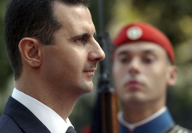 ARCHIVO - El presidente de Siria, Bashar Assad, pasa revista a la guardia presidencial durante una ceremonia de bienvenida en Atenas, el 15 de diciembre de 2003. (AP Foto/Petros Giannakouris, Archivo)