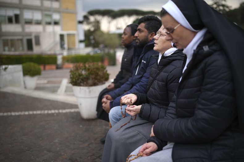 Monjas rezan por Francisco frente a la estatua del papa Juan Pablo II, en el exterior del policlínico Agostino Gemelli de Roma, el 20 de febrero de 2025. El pontífice argentino está ingresado en el centro desde el 14 de febrero. (AP Foto/Alessandra Tarantino)