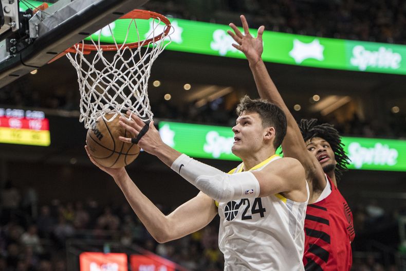 El jugador del Jazz de Utah Walker Kessler (24) sostiene la pelota junto al jugador de los Trail Blazers de Portland Shaedon Sharpe en la segunda mitad de su juego de NBA el sábado 2 de diciembre de 2023 en Salt Lake City. (AP Foto/Isaac Hale)