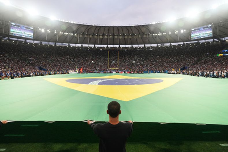 Unas cuadrillas despliegan una bandera brasileña en el terreno de juego antes de un partido de fútbol americano de la NFL entre los Cowboys de Dallas y los Ravens de Baltimore en Río de Janeiro, el 27 de septiembre de 2026. (Foto AP/Fernando Llano)