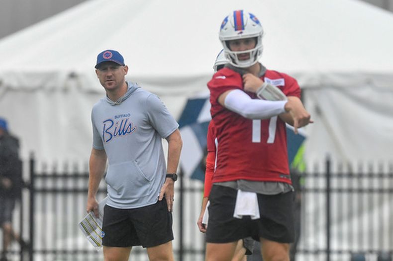 Joe Brady, izquierda, head coach de los Bills de Buffalo, observa al quarterback Josh Allen (17) mientras lanza el balón durante la práctica del equipo en el campamento de entrenamiento, el miércoles 29 de julio de 2026, en Pittsford, Nueva York. (AP Foto/Adrian Kraus)