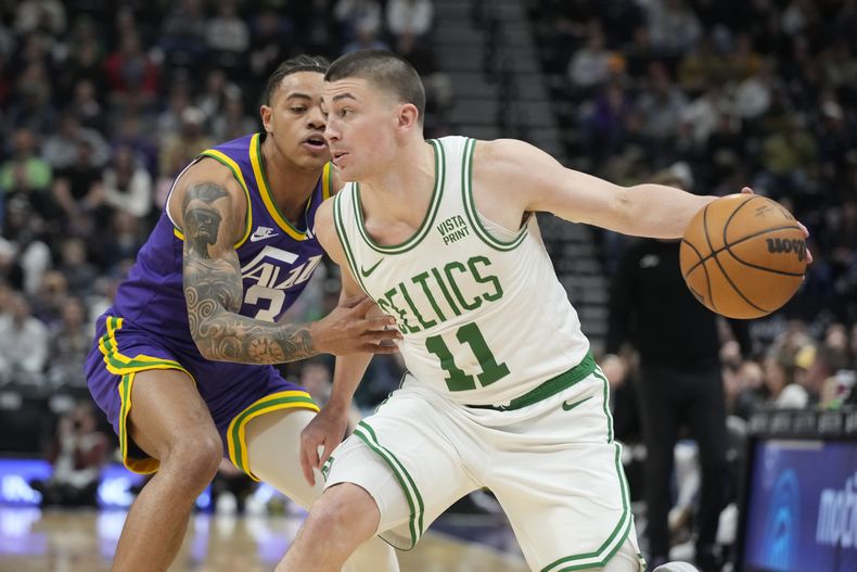 El base de los Celtics de Boston Payton Pritchard avanza hacia la canasta con el balón mientras lo defiende el base del Jazz de Utah Keyonte George en el encuentro de la NBA del martes 12 de marzo del 2024. (AP Foto/George Frey)