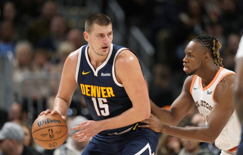Nikola Jokic, izquierda, de los Nuggets de Denver, busca colarse rumbo a la canasta ante la marca defensiva de Charles Bassey, derecha, de los Spurs de San Antonio, quien lo presiona durante la primera mitad del juego de baloncesto de la NBA, el domingo 26 de noviembre de 2023, en Denver. (AP Foto/David Zalubowski)