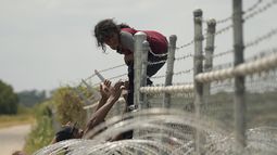 Migrantes que cruzaron el río Bravo (o Grande) desde México hacia Estados Unidos escalan por una cerca con alambre de púas, el lunes 21 de agosto de 2023, en Eagle Pass, Texas. (AP Foto/Eric Gay, Archivo)