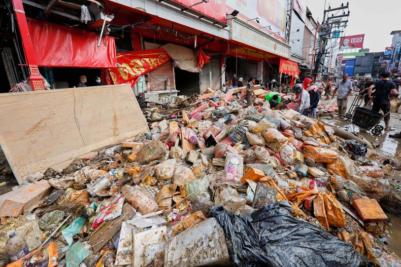 Personas caminan cerca de bienes dañados por las inundaciones en la provincia de Songkhla, en el sur de Tailandia, el sábado 29 de noviembre de 2025. (Foto AP/Sarot Meksophawannakul)