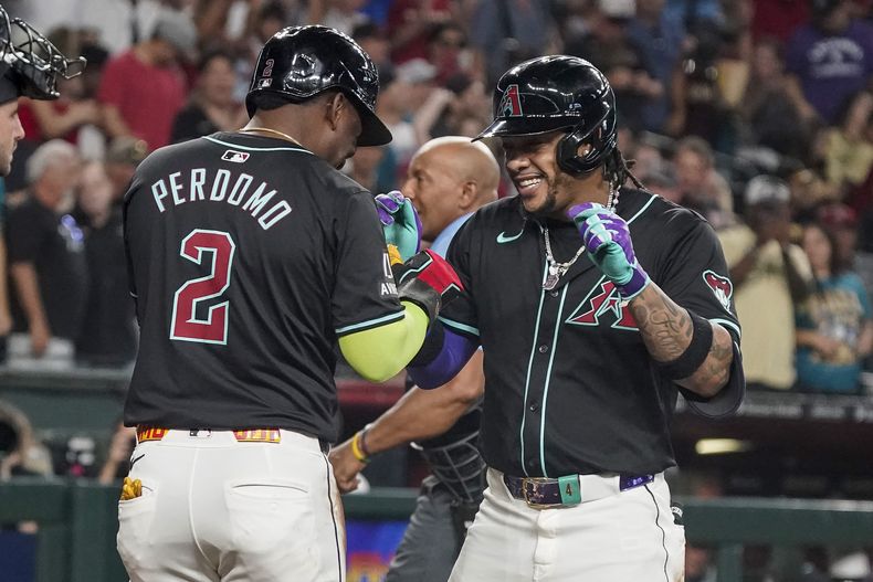 Geraldo Perdomo (2), de los Diamondbacks de Arizona, baila en el plato con Ketel Marte después del jonrón de dos carreras de Marte durante la segunda entrada contra los Piratas de Pittsburgh, el sábado 27 de julio de 2024, en Phoenix. (AP Foto/Darryl Webb)