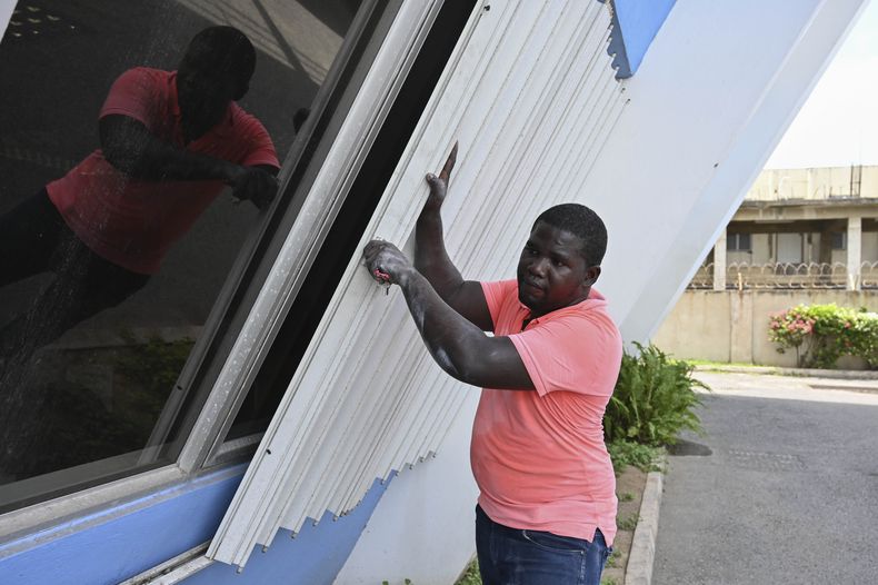Un hombre cubre las ventanas de un edificio para protegerlas de la llegada del huracán Beryl, en Kingston, Jamaica, el 2 de julio de 2024. (AP Foto/Collin Reid)