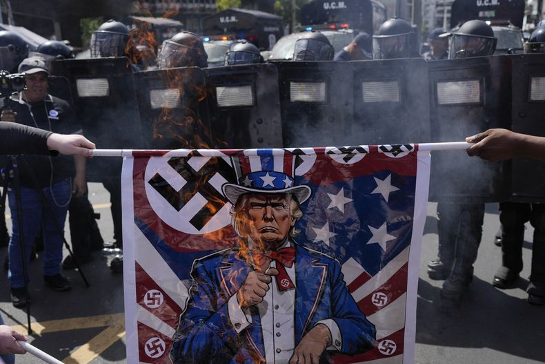 Manifestantes queman afiches que muestran al presidente estadounidense Donald Trump vestido del tío Sam durante un mitin contra la visita del secretario de Estado de Estados Unidos, Marco Rubio, el domingo 2 de febrero de 2025, en Ciudad de Panamá. (AP Foto/Matías Delacroix)
