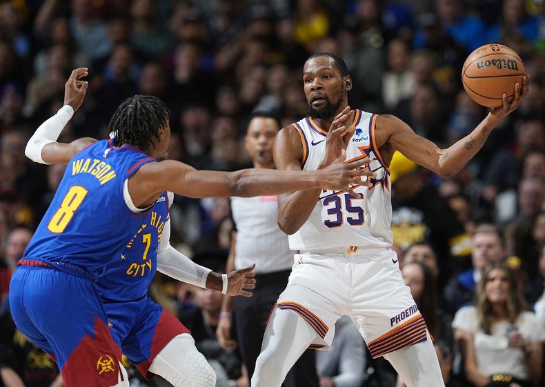 Kevin Durant, alero de los Suns de Phoenix, busca enviar un pase frente a Peyton Watson, de los Nuggets de Denver, el martes 5 de marzo de 2024 (AP Foto/David Zalubowski)