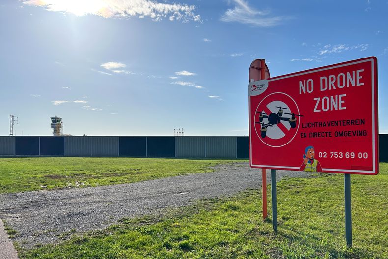 Una torre de control, a la izquierda, y un letrero que prohíbe el vuelo de drones en la zona, afuera del Aeropuerto Internacional de Bruselas, en Zaventem, Bélgica, el miércoles 5 de noviembre de 2025. (AP Foto/Virginia Mayo)