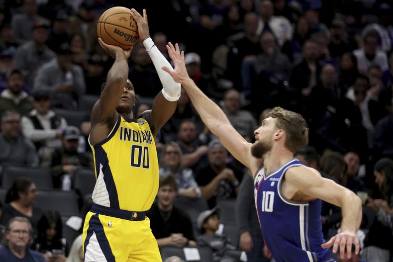Bennedict Mathurin, base de los Pacers de Indiana, dispara frente a Domantas Sabonis, de los Kings de Sacramento, durante la segunda mitad del partido del jueves 18 de enero de 2024 (AP Foto/Jed Jacobsohn)