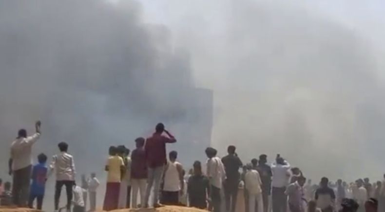 Gente mira una humareda después de que un avión se estrellara en Ahmedabad, en el estado de Gujarat, India, el jueves 12 de junio de 2025. (Mohan Nakum via AP)