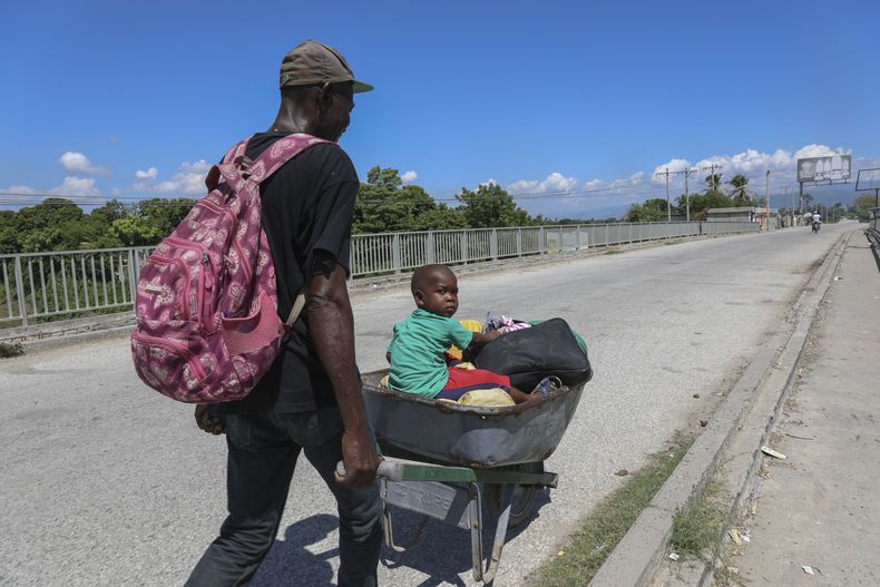 Un hombre empuja a un niño en una carretilla en Pont-Sonde, Haití, el 7 de octubre del 2024, días después de una matanza en esa área. (AP Foto/Odelyn Joseph)