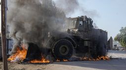 Un vehículo militar israelí retira neumáticos en llamas que bloquean una carretera durante una incursión del ejército en el campo de refugiados de Faraa, en Cisjordania, el 8 de diciembre de 2023. (AP Foto/Majdi Mohammed)